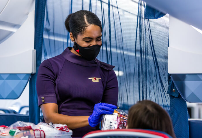 An airline attendant hands a product to a customer.