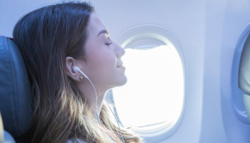 woman with headphones closed eyes relaxed on a plane