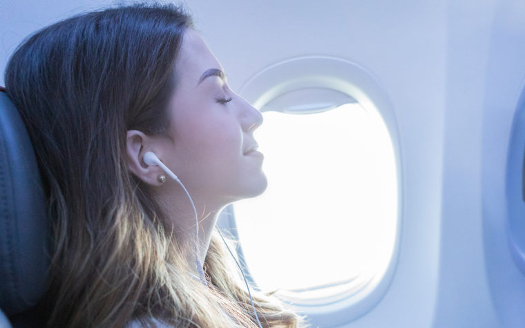 woman with headphones closed eyes relaxed on a plane