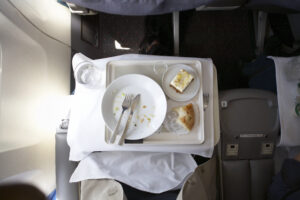 Plate and cutlery on tray table in airplane, overhead view