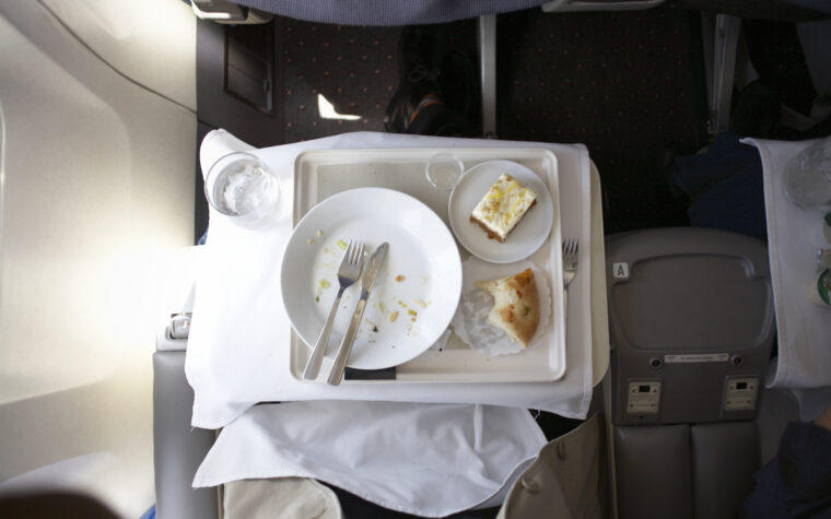 Plate and cutlery on tray table in airplane, overhead view