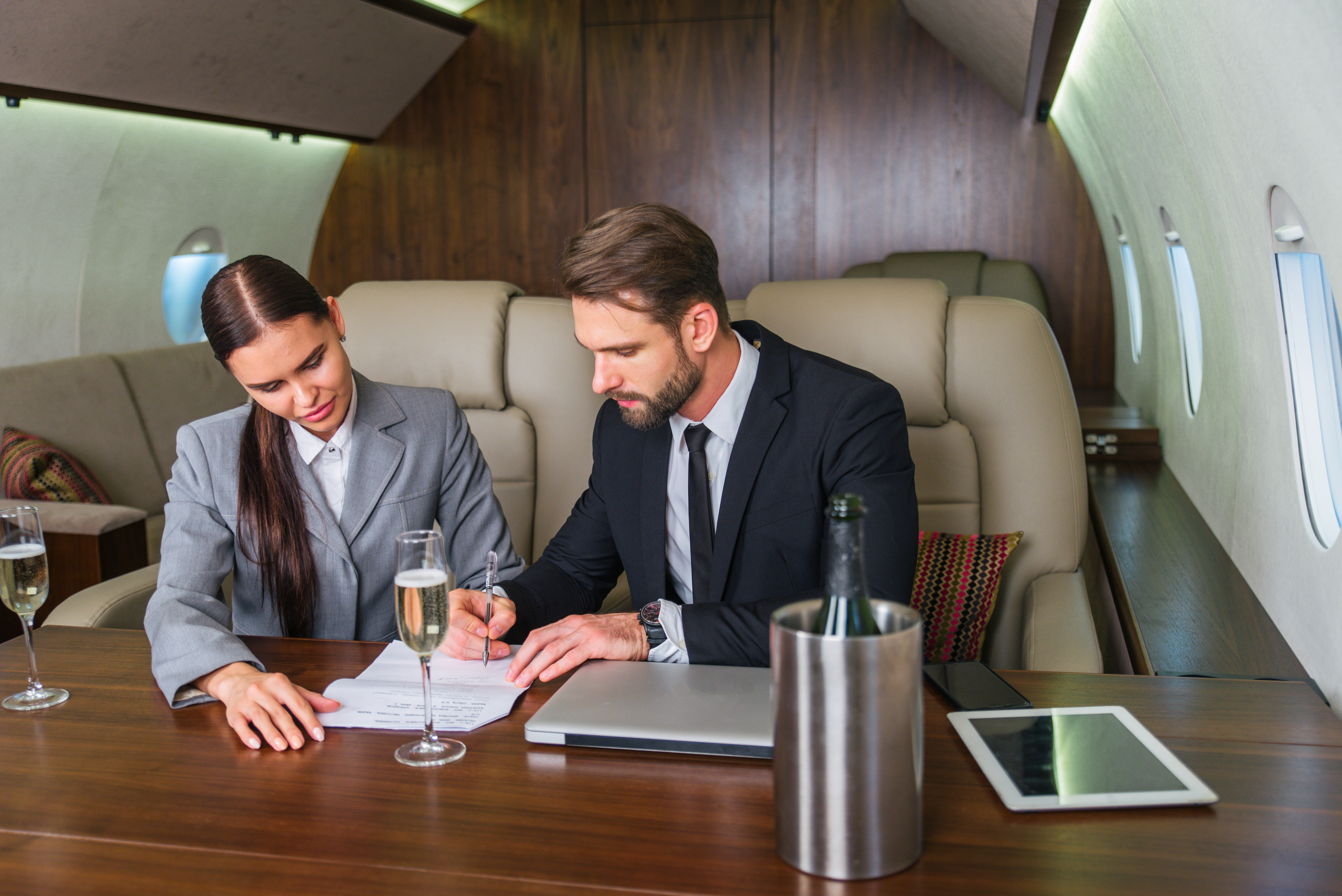 Businessman and woman working while travelling on private jet - Portrait of business people taking a first class flight for work, concepts about business and mobility