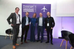 passenger experience conference delegates in front of purple sign