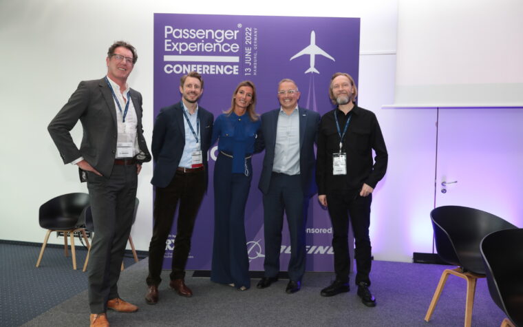 passenger experience conference delegates in front of purple sign