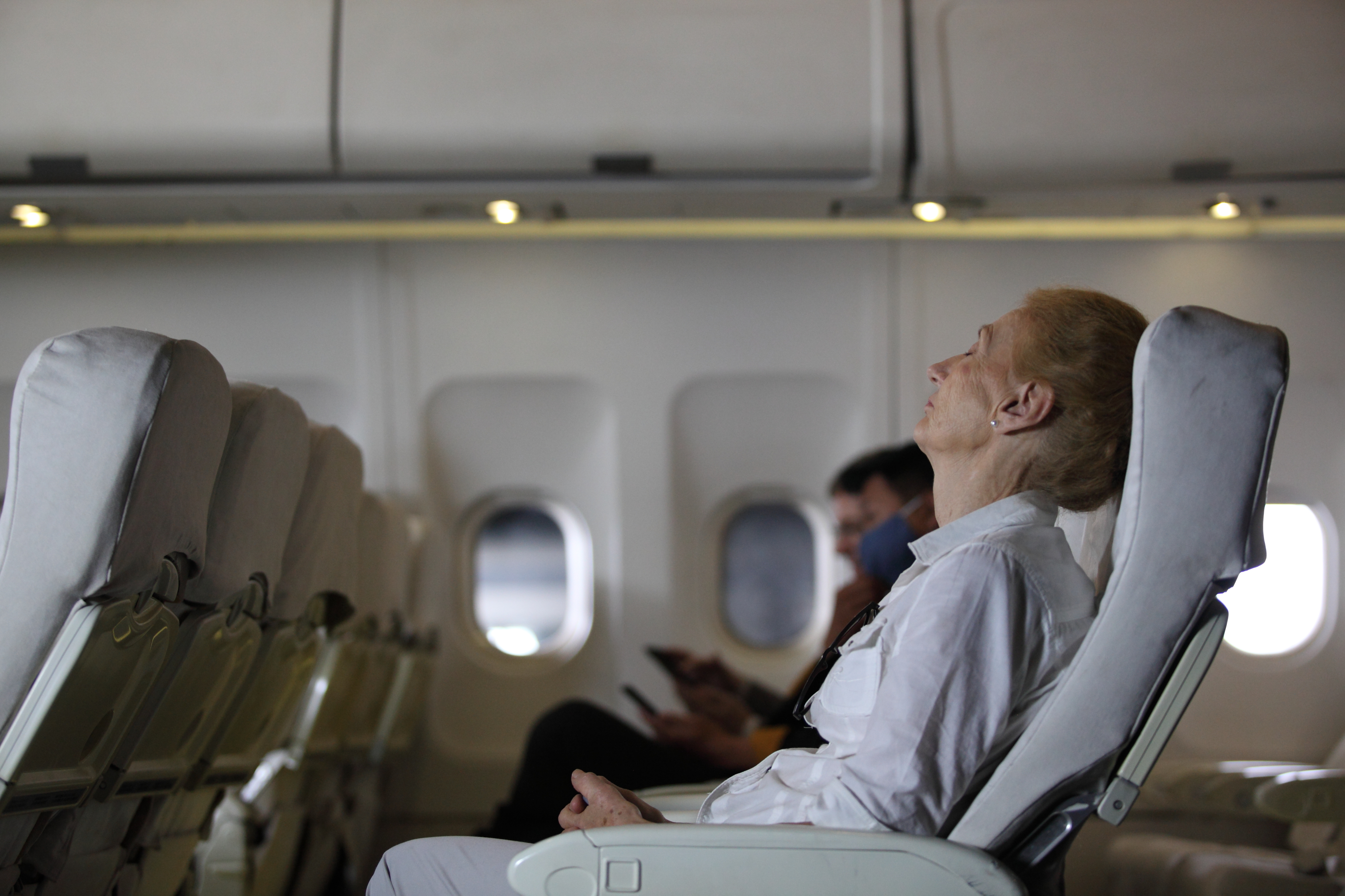 passenger lady napping on uncomfortable seat while traveling by airplane. Commercial transportation by planes.Female passenger sleeping